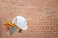 Bricklayer tools. Brick, white helmet, trowel and construction square, Red brick wall background. Concept of the construction Royalty Free Stock Photo