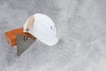 Bricklayer tools - trowel, bricks and white helmet on cement background. copyspace