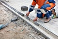 The bricklayer uses a black marker and an aluminum level to measure out a portion of the paving slabs for alignment on the Royalty Free Stock Photo