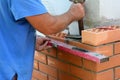 Bricklayer using a spirit level to check bricklaying wall corner. Builder contructor laying brick wall house corner