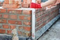 Bricklayer using a spirit level to check new brick foundation wall. Brick house wall foundation with bitumen wateproof barrier Royalty Free Stock Photo