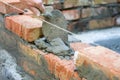 Bricklayer using trowel to tap a brick level. Hand white-wash cement built wall brick new house, Bricklayer worker installing bric
