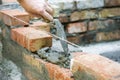 Bricklayer worker installing brick masonry on exterior wall. Professional construction worker laying bricks. Bricklayer worker
