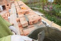 Bricklayer worker installing red blocks and caulking brick masonry joints exterior brick house wall with trowel putty knife outdo Royalty Free Stock Photo