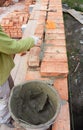 Bricklayer Worker Installing Red Blocks and Caulking Brick Masonry Joints Exterior Wall with Trowel putty Knife. Royalty Free Stock Photo