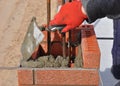 Bricklayer worker installing red blocks and caulking brick masonry Royalty Free Stock Photo