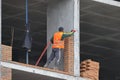 A bricklayer works at a construction site. Work is underway to lay a red brick wall. A new house is being built.