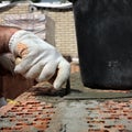 Bricklayers hands with in masonry trowel bricklaying new house wall on foundation. Close up of industrial bricklayer installing Royalty Free Stock Photo