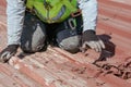 Bricklayers scraping the waterproofing off a roof with a trowel to prevent dampness in the buildings