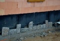 Bricklayers tiling the house with sandstone stones. They connect stones with cement. behind the cladding is insulation with knobs