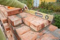 Bricklaying, Brickwork. Close up Bricklaying on House Cnstruction Site. Bricklayer Using a Spirit Level to Check Brick Wall O Royalty Free Stock Photo