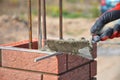 Bricklaying closeup. Bricklayer hand holding a putty knife and building a brick fence column.