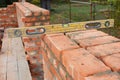 Bricklaying with Spirit Level to Check New Red Brick House Wall. Royalty Free Stock Photo