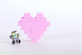The bricks of the plastic constructor in the form of pink heart whith little robot. White background. Royalty Free Stock Photo