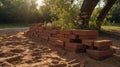 Rustic Brown Bricks Stacked on Sandy Ground near Lush Greenery Royalty Free Stock Photo