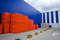 Bricks stack wrapped in orange stretched plastic near large hardware store.