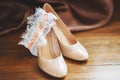 Bridal beige wedding shoes with garter, wooden background. Marriage concept Royalty Free Stock Photo