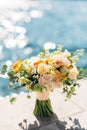 Bridal bouquet of cream roses, eucalyptus tree branches, yellow and orange buttercups, not blooming buds of white