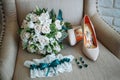 Bridal bouquet, earrings with green stones, garter of the bride, shoes on the chair Royalty Free Stock Photo