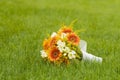 Bridal bouquet laying on green grass. Beautiful romantic white and orange wedding flowers with copy space and blurred background. Royalty Free Stock Photo