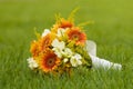 Bridal bouquet laying on green grass. Beautiful romantic white and orange wedding flowers with copy space and blurred background. Royalty Free Stock Photo