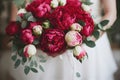 Bridal bouquet with lush bright scarlet peonies and green leaves.