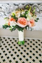 Bridal bouquet near the white vintage wall on the white wooden floor