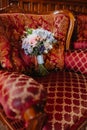 Bridal bouquet with pink roses and long ribbons on a red armchair