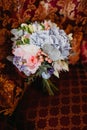 Bridal bouquet with pink roses and long ribbons on a red armchair