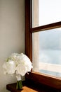 Bridal bouquet of pure white roses, babys breath, white ribbons and brooch on the window