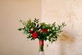 Bridal bouquet of red and pink roses, boxwood branches, not blooming buds of white flowers and red ribbons with brooch Royalty Free Stock Photo