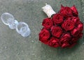 Bridal bouquet with red roses next to wine glasses