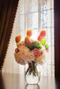 Bridal bouquet of spring flowers : tulips, roses in vase on the table , window as a background