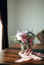 Bridal bouquet of white and pink peonies, olive branches, lavender and campanula with pink ribbons in the glass vase on