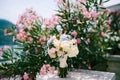 Bridal bouquet of white and pink roses, babys breathe, scabiosa, hortense and white ribbons near the blooming oleander