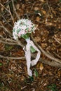 Bridal bouquet of white and pink roses, wild berries, eustoma with white lace ribbons on the dry brunch, liyng on the