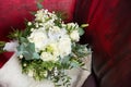 A bridal bouquet of white roses against the background of an old burgundy leather armchair. Retro, vintage style. Royalty Free Stock Photo
