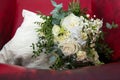 A bridal bouquet of white roses against the background of an old burgundy leather armchair. Retro, vintage style. Royalty Free Stock Photo