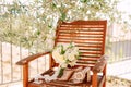 Bridal bouquet of white roses, freesia, boxwood branches and white ribbons near the shoes of the bride on the wooden