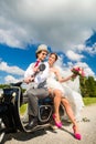 Bridal couple driving motor scooter wearing gown and suit Royalty Free Stock Photo