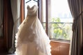 Bridal elegance Wedding dress hangs on a curtain rail near window