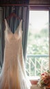 Bridal elegance Wedding dress hangs on a curtain rail near window