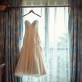 Bridal elegance Wedding dress hangs on a curtain rail near window