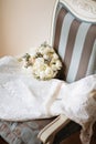 Wedding rustic bouquet and white dress on vintage striped chair. Bridal room interior.