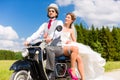 Bridal pair driving motor scooter wearing gown and suit Royalty Free Stock Photo