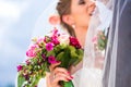 Bridal pair kissing under veil at wedding