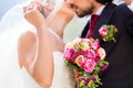 Bridal pair kissing under veil at wedding