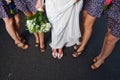 A bridal party ladies stand on a road and display their shoes