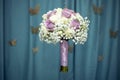 Bridals bouquet with purple roses, levitating on blue fabric folds background Royalty Free Stock Photo