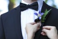 Bride adjusting boutonniere on grooms jacket